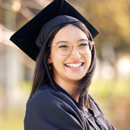 Smiling woman wearing a graduation cap and gown.